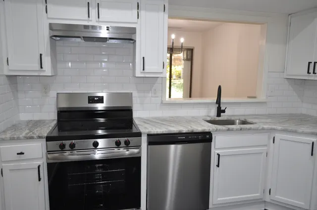 a kitchen with stainless steel appliances granite countertop a sink stove and cabinets