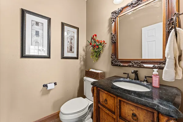 a bathroom with a granite countertop toilet a sink and a mirror