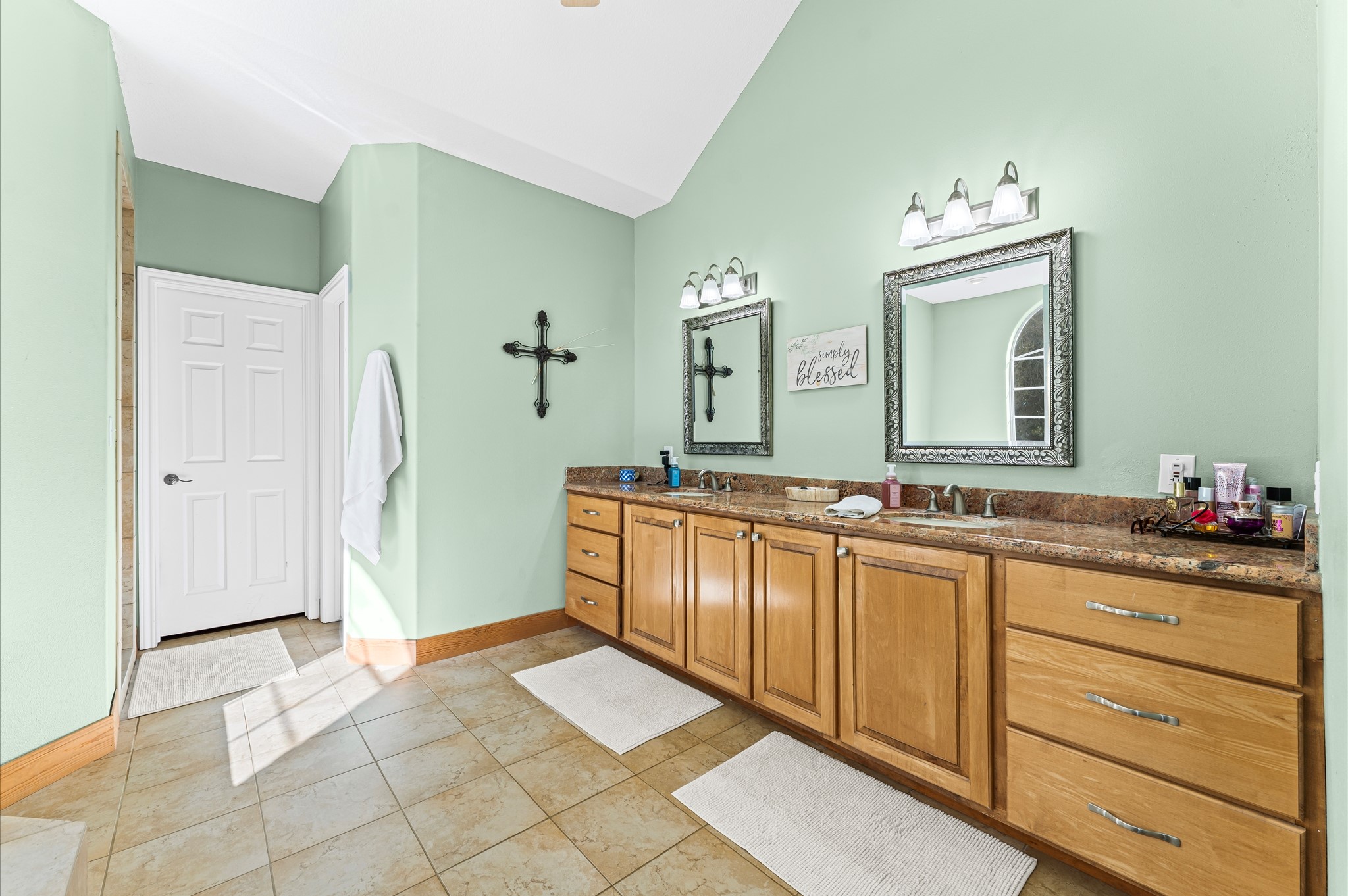 21550-21554 Mueschke Road Tomball, TX 77377 - Photo 14 of 42 This spacious bathroom features a double vanity with granite countertops and ample storage in wooden cabinets. The light green walls complement the tile flooring, and the room is well-lit.