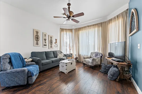 a living room with furniture floor to ceiling window and a ceiling fan