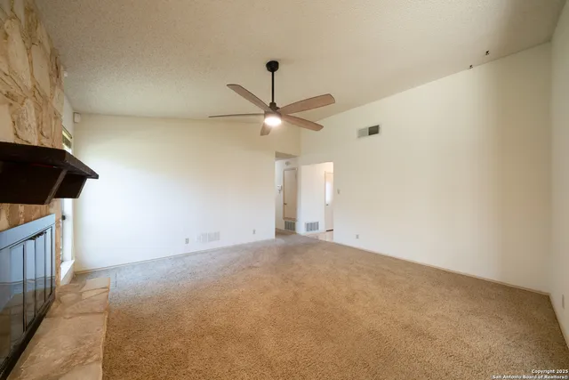an empty room with ceiling fan and window