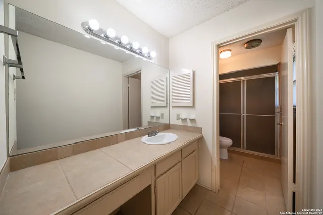 a bathroom with a granite countertop sink a toilet and shower