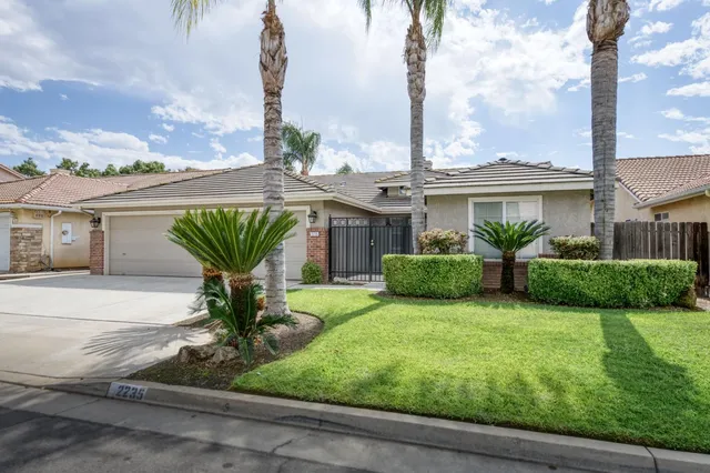 a front view of a house with a garden and palm trees