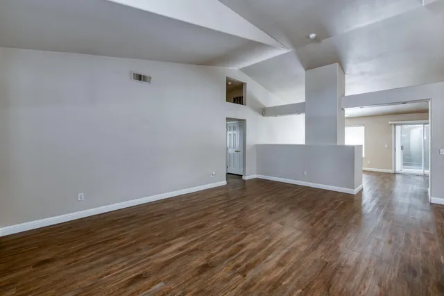 a view of an empty room with wooden floor and closet