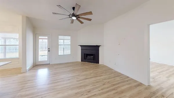 a view of an empty room with a window and wooden floor