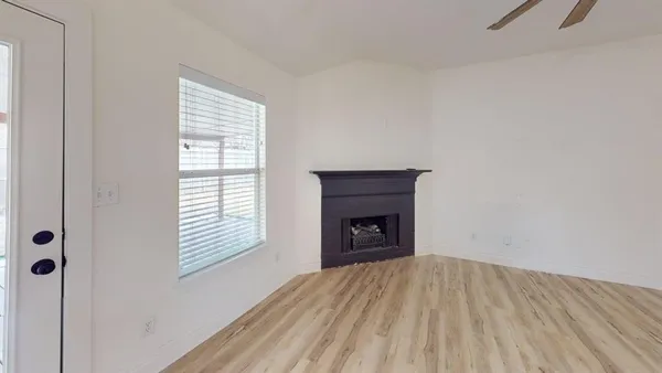 a view of empty room with wooden floor and fireplace