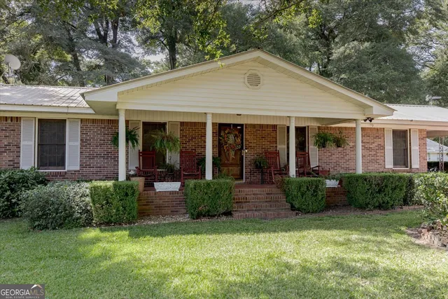 a front view of a house with porch and garden