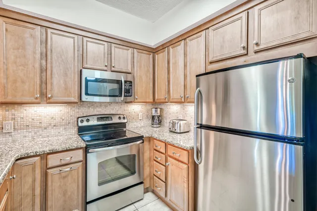 a kitchen with granite countertop a refrigerator stove and microwave