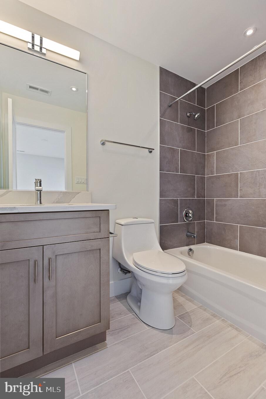 14732 Patuxent Avenue Solomons, MD 20688 - Photo 22 of 31 a bathroom with a toilet a sink a mirror a bathtub and shower