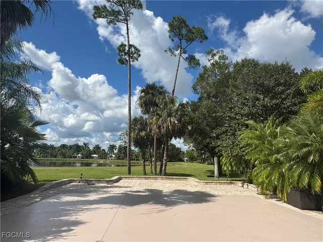 a view of a house with a big yard and palm trees