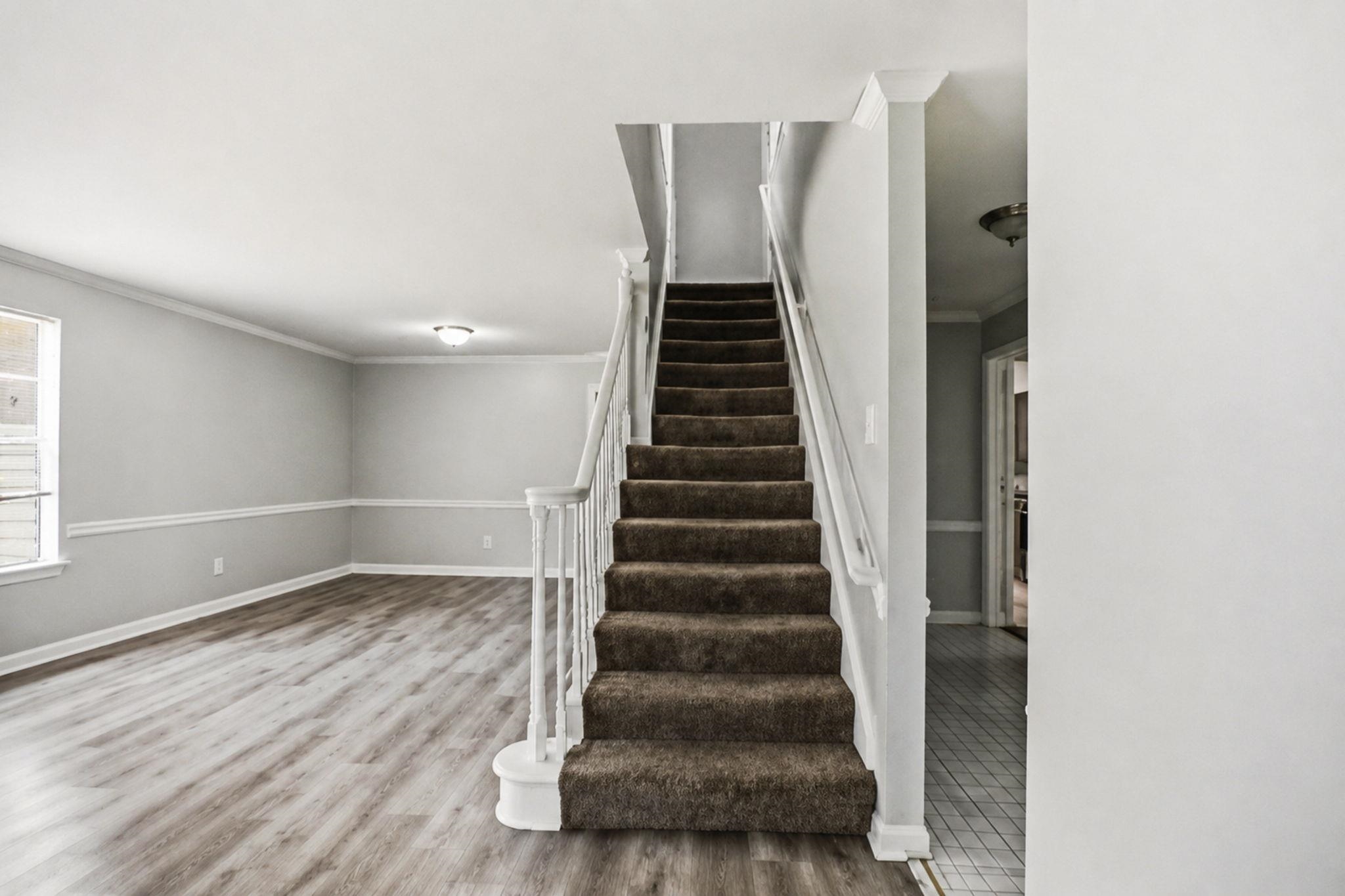 3113 Raleigh Ridge Cove Memphis, TN 38128 - Photo 9 of 38 Carpeted staircase with white balusters, wood-finish flooring, white baseboards, crown molding, and a flush mount ceiling light fixture