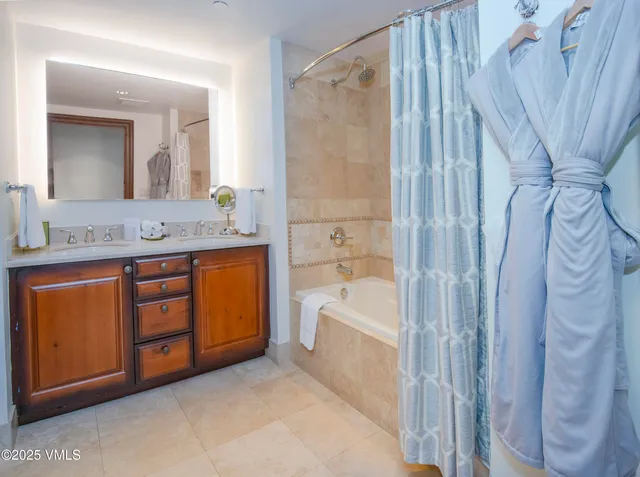 a bathroom with a granite countertop sink a mirror a bathtub and shower