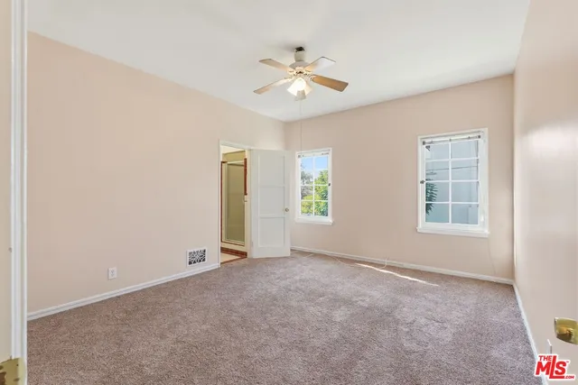 an empty room with a chandelier fan and windows
