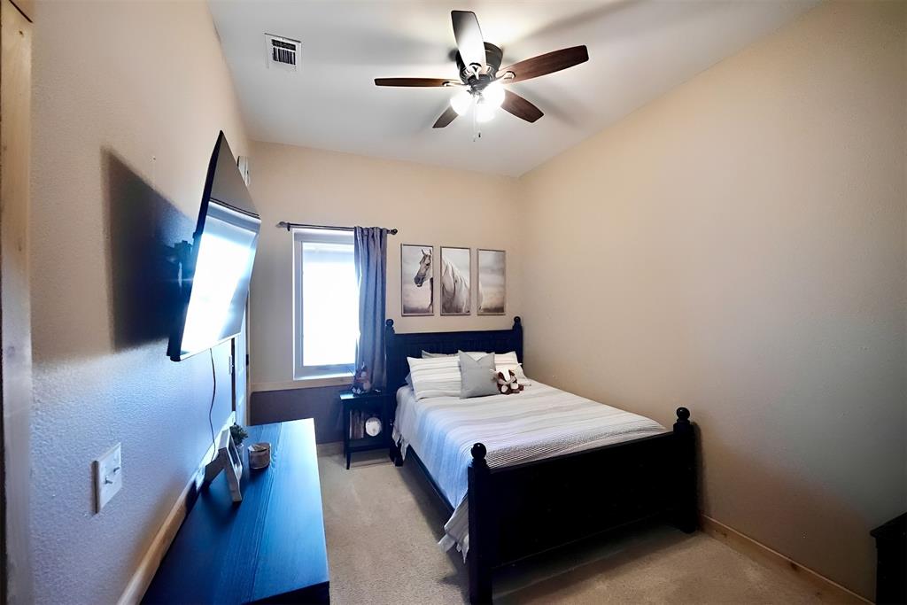 290 Barton Road Maypearl, TX 76064 - Photo 19 of 32 a bedroom with a large bed and a chandelier