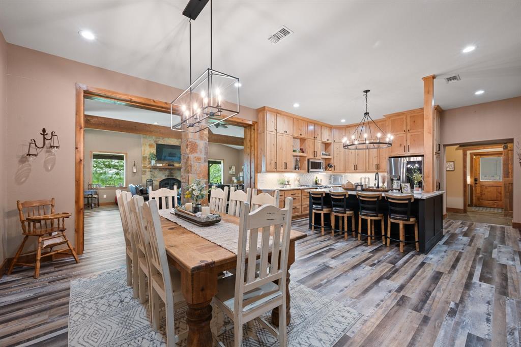 290 Barton Road Maypearl, TX 76064 - Photo 7 of 34 a dining room with wooden floor a chandelier a wooden table and chairs
