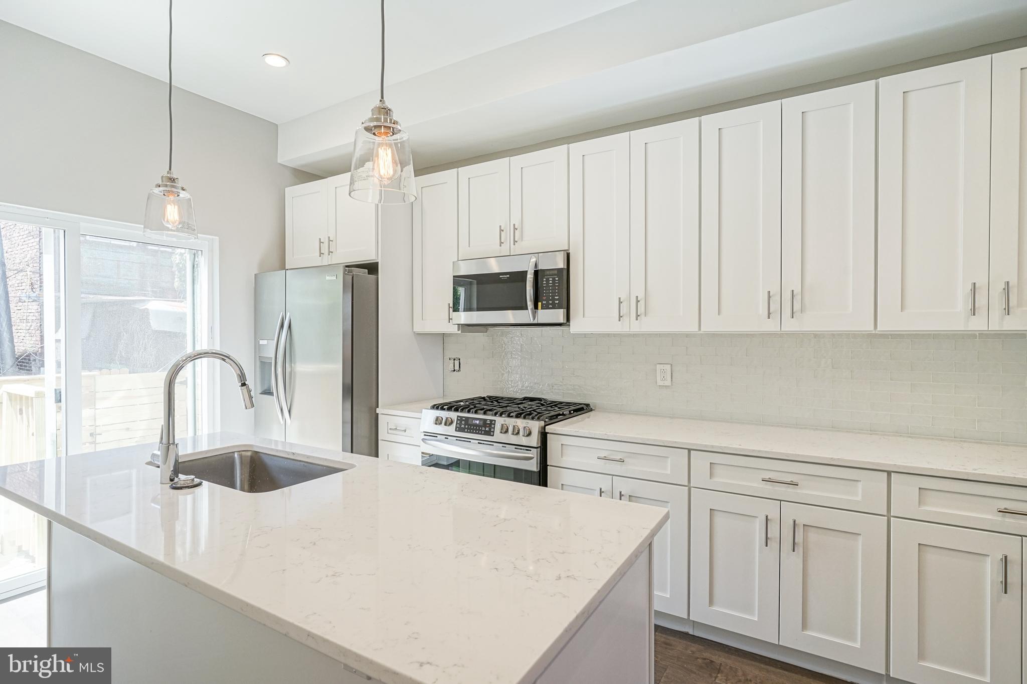542 Pierce Street Philadelphia, PA 19148 - Photo 12 of 36 a kitchen with white cabinets a sink and stainless steel appliances