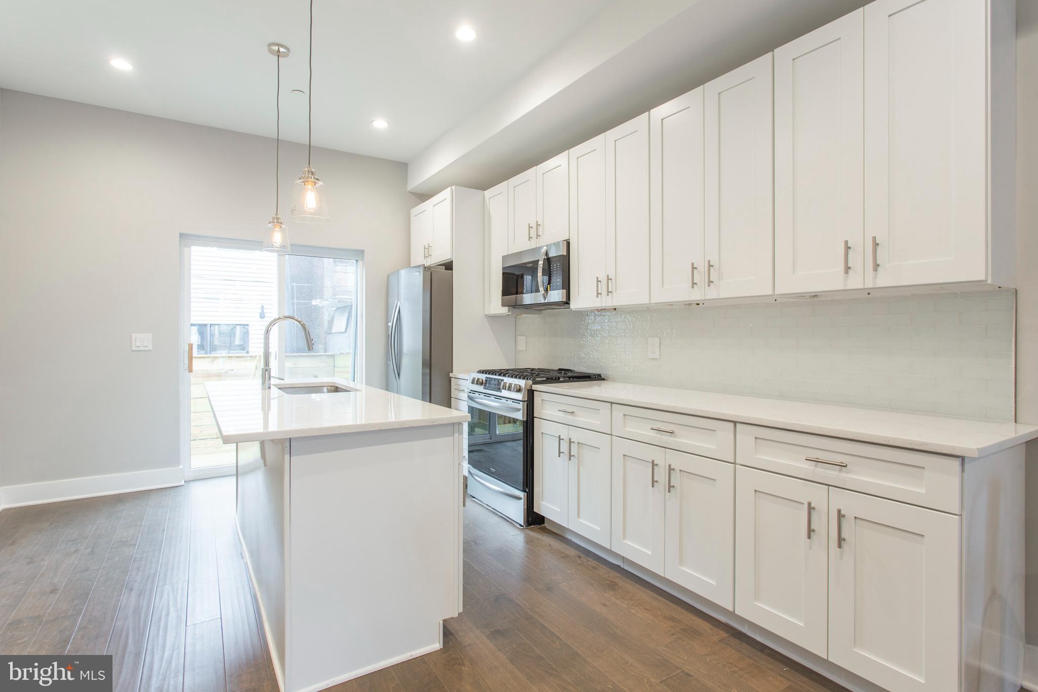 542 Pierce Street Philadelphia, PA 19148 - Photo 8 of 36 a kitchen with kitchen island granite countertop a sink cabinets and stainless steel appliances