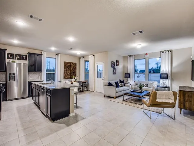a living room with stainless steel appliances furniture a rug and a view of kitchen