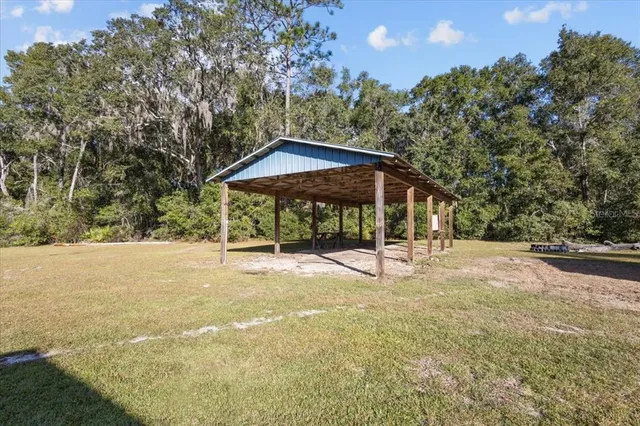 a view of a wooden house with a yard and sitting area