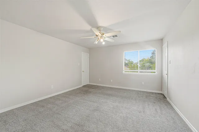 an empty room with windows and fan