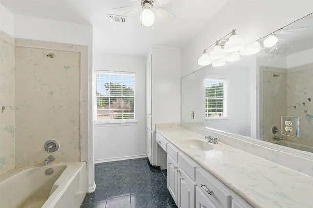 a bathroom with a granite countertop sink a large mirror and a bathtub