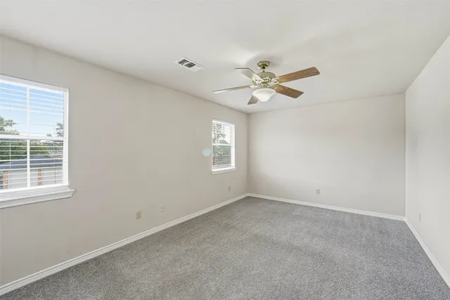 an empty room with a window and a ceiling fan