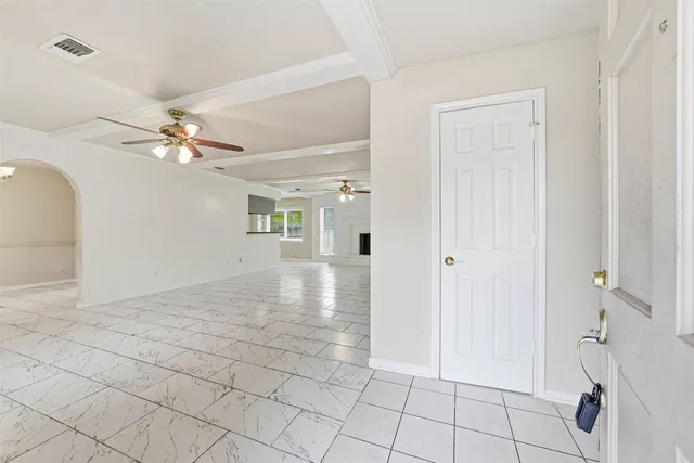 a view of an empty room and chandelier fan