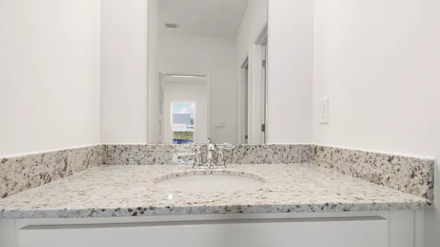 a bathroom with a granite countertop sink and white cabinets