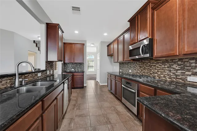 a kitchen with kitchen island granite countertop a sink stainless steel appliances and cabinets