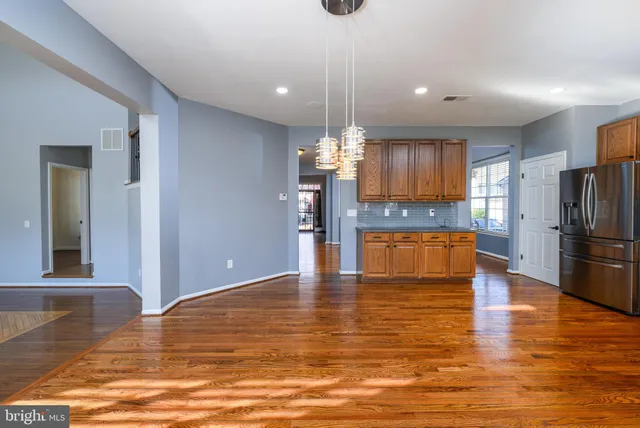 a view of a kitchen with kitchen island a window wooden floor and stainless steel appliances