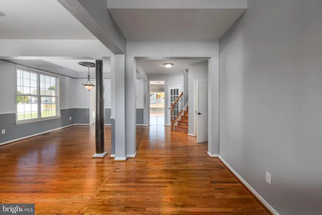 a view of a hallway with wooden floor and a living room