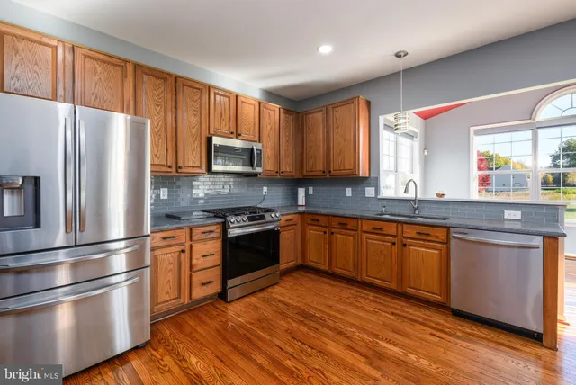 a kitchen with stainless steel appliances granite countertop a refrigerator stove top oven and sink