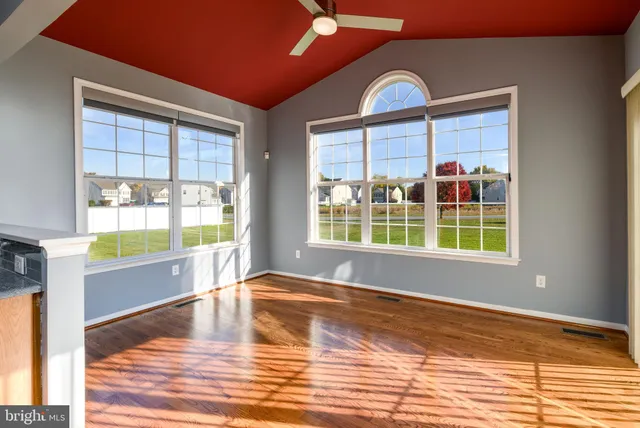 a view of empty room with wooden floor and fan