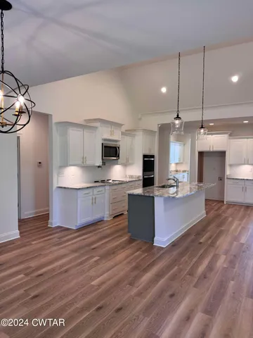 a large kitchen with stainless steel appliances a large counter top a sink a stove and a refrigerator