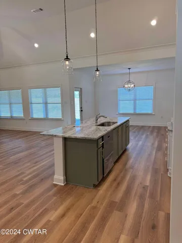 a kitchen with stainless steel appliances granite countertop a sink a stove and a wooden floors