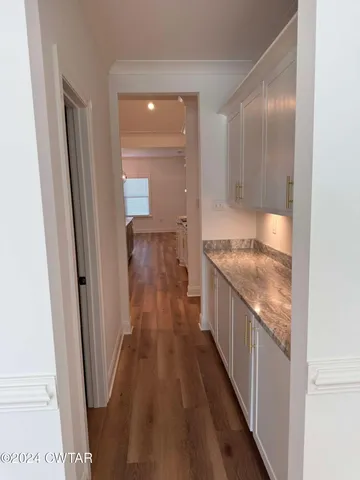 a hallway with granite countertop a sink and wooden floor