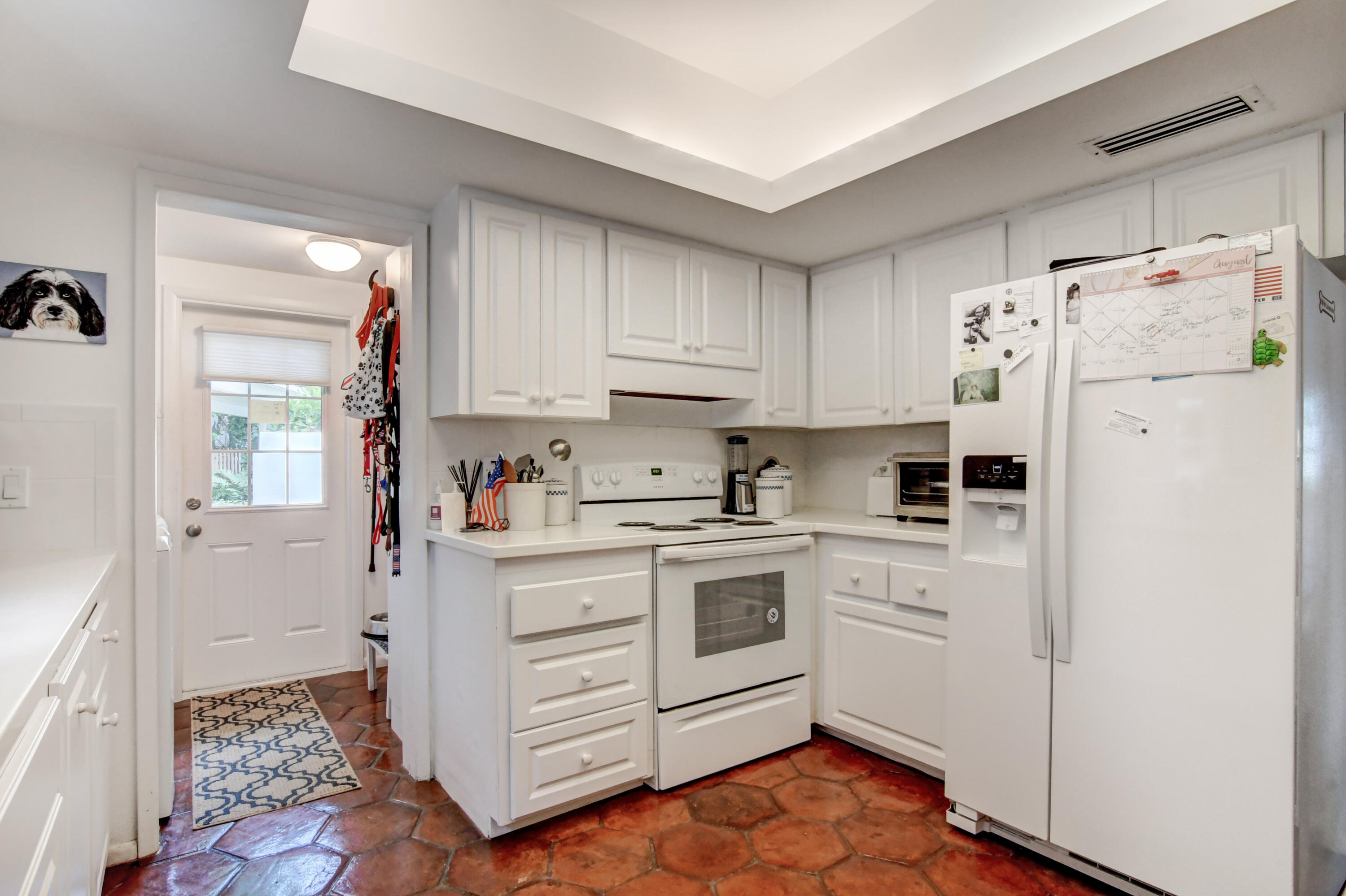 801 North Ocean Boulevard Delray Beach, FL 33483 - Photo 16 of 37 a kitchen with white cabinets and white appliances