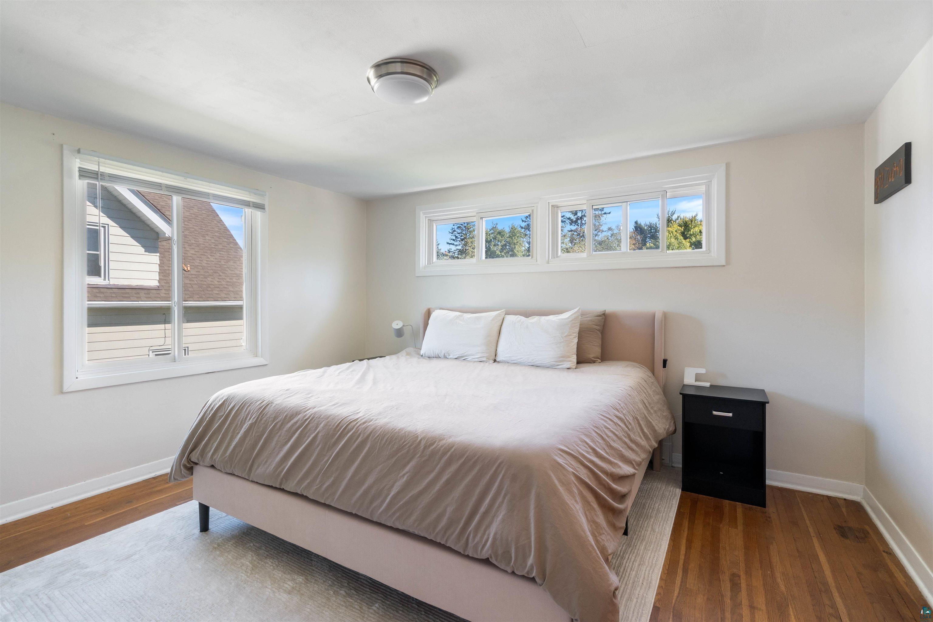 3715 Rendle Avenue Duluth, MN 55803 - Photo 8 of 20 Hardwood flooring, multiple windows, ceiling-mounted light fixture, white trim, and light-toned wall paint