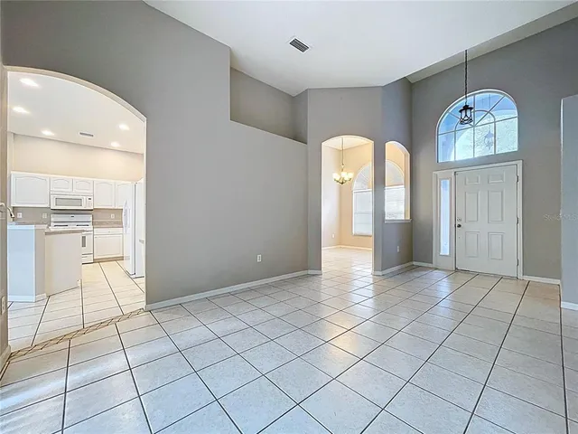 a view of an empty room with window and chandelier fan