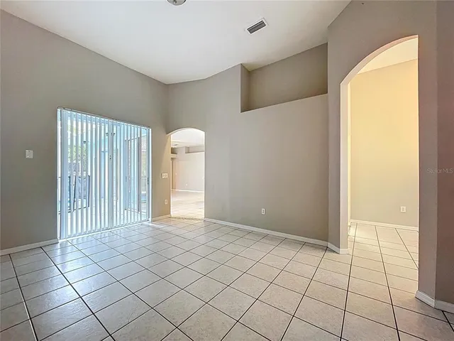 an empty room with a chandelier fan and windows