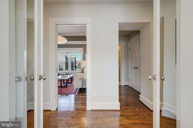 a view of a hallway with wooden floor closet and windows