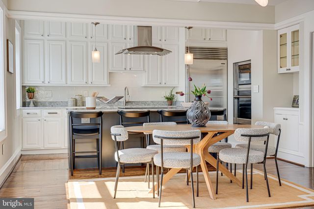 a kitchen with stainless steel appliances a white table chairs and a refrigerator