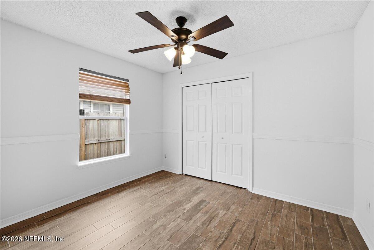 425 3rd Street West Baldwin, FL 32234 - Photo 23 of 47 an empty room with wooden floor ceiling fan and windows