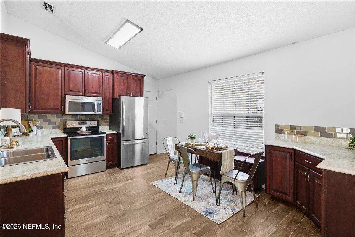 425 3rd Street West Baldwin, FL 32234 - Photo 10 of 47 a kitchen with stainless steel appliances granite countertop a stove top oven a sink dishwasher a dining table and chairs with wooden floor