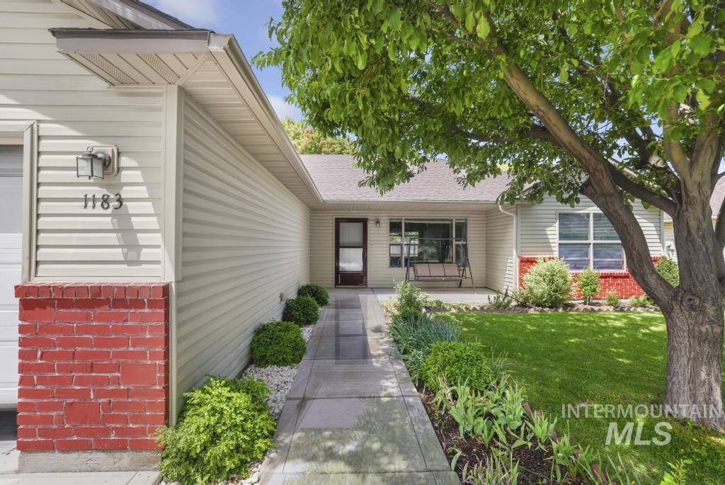 1183 Cortes Loop Twin Falls, ID 83301 - Photo 3 of 30 Exterior featuring light-colored siding with red brick accents, a concrete walkway, mature landscaping, and a covered porch area