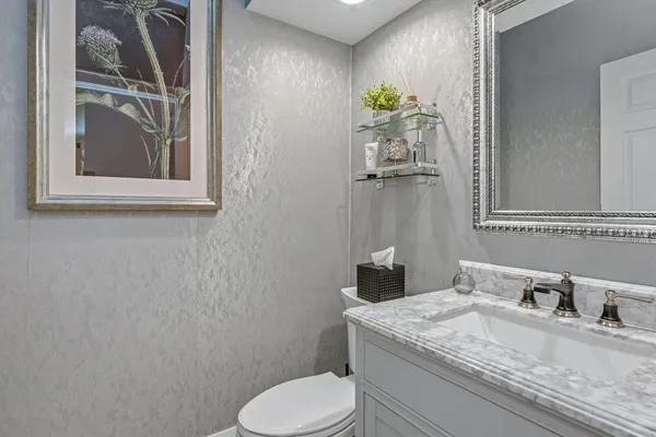 a bathroom with a granite countertop toilet sink and mirror