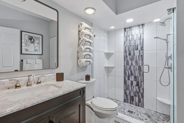 a bathroom with a granite countertop sink a toilet and shower
