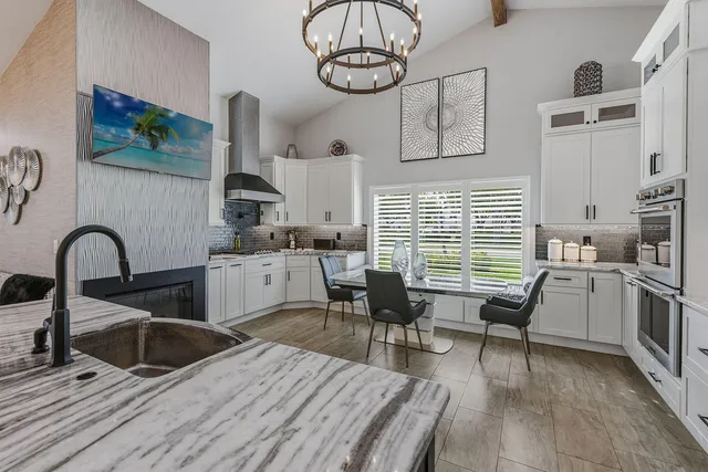 a kitchen with stainless steel appliances granite countertop a stove a sink dishwasher and white cabinets with wooden floor