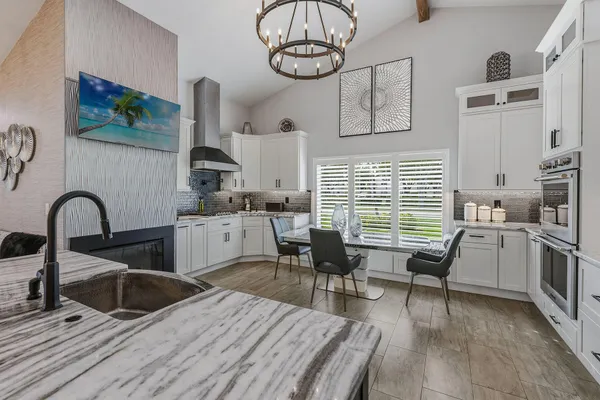a kitchen with stainless steel appliances granite countertop a stove a sink dishwasher and white cabinets with wooden floor