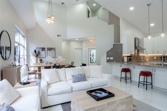 a living room with stainless steel appliances kitchen island a table and chairs